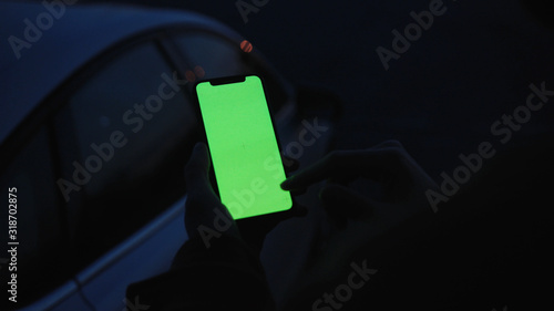 Lviv, Ukraine - May 19, 2018: On dark man hands holding use touch phone with vertical green screen street background sunset busy finger touch message cellphone display girl slow motion