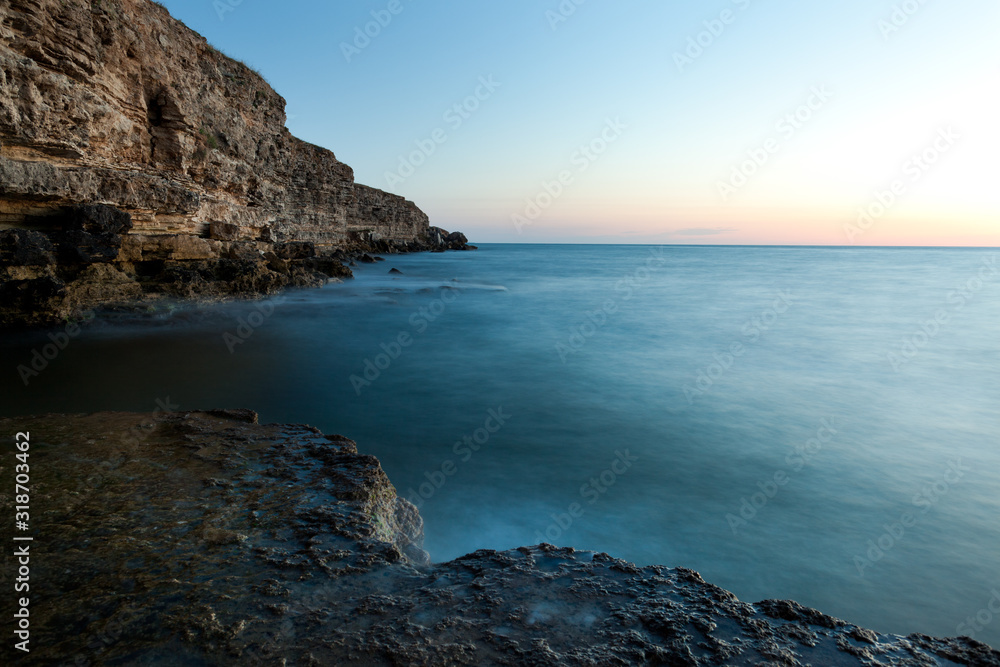 Beautiful sunset over wavy stormy Black sea rocky coastline in Crimea on summer day. Natural landscape background and wallpaper