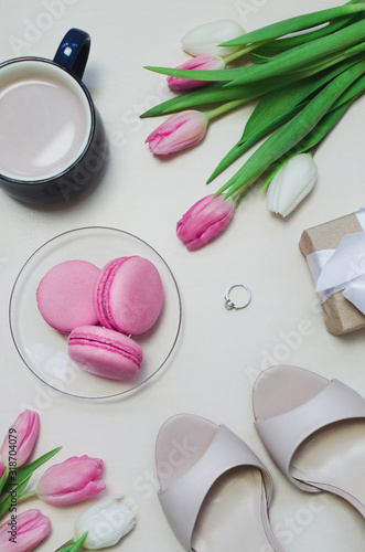 Coffee cup  spring tulip flowers and pink macarons on pastel table top view vertical. Greeting for Womans or Mothers Day