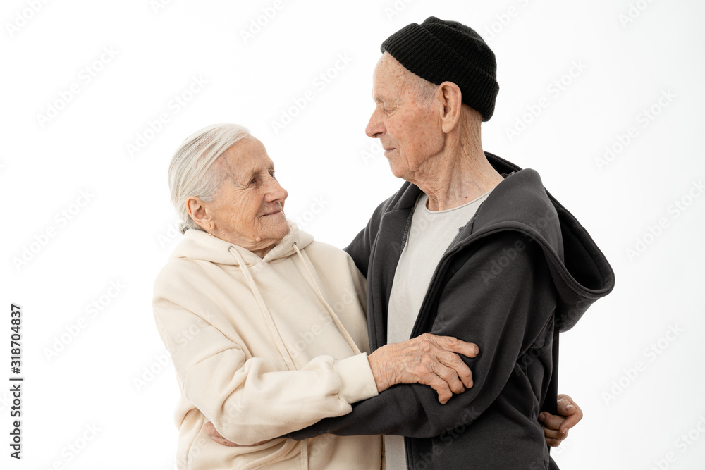 Attractive lovely old seniors couple in hoodies dancing isolated over white background Attractive lovely old seniors couple in hoodies dancing isolated over white background