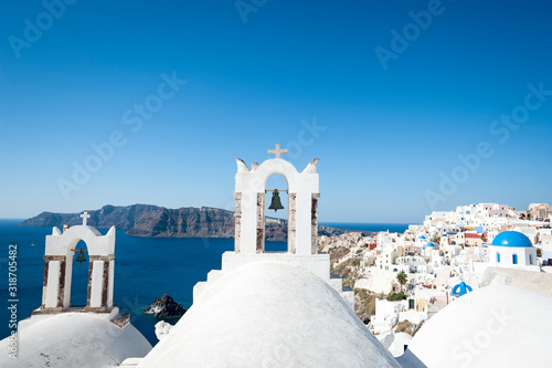 Bright scenic view of whitewashed church domes dominating the frame in the Mediterranean hillside village of Oia in Santorini, Greece