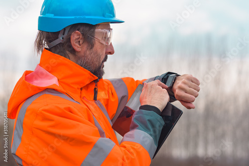 Forestry technician checking up on his smart watch