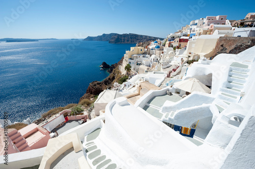 Classic Santorini staircases wind their way along bright morning hillside view of Oia village
