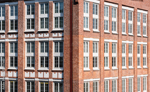 Large office building in brick with huge white windows.