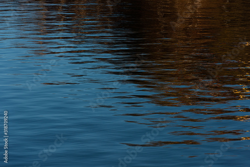 Water with small waves. Reflections of blue sky and buildings.