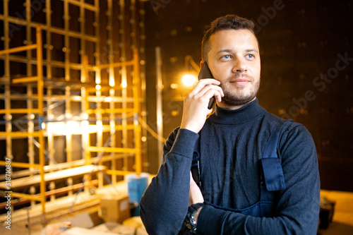 Worker talking on the phone. Serious man phoning to discuss task and solve problem. Renovation at home. Building construction indoor. .. photo