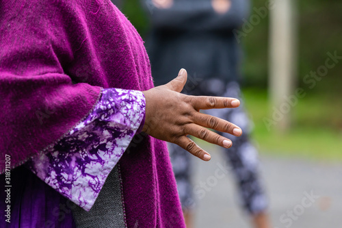 Closeup of female wearing full sleeve purple dress while making hand gesture telling story during festival at world and spoken word festival