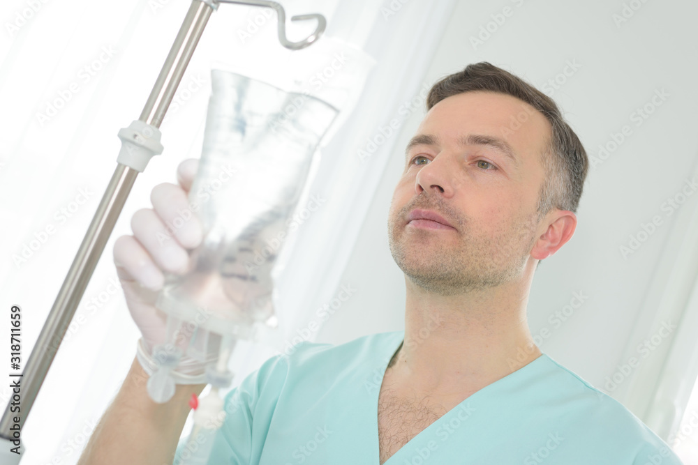 portrait of a male nurse adjusting a perfusion bag portrait of a male nurse adjusting a perfusion bag