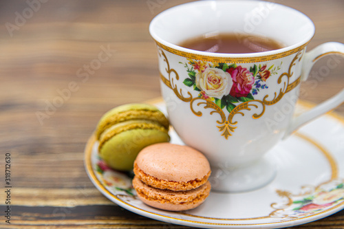Cup of tea with macaroons on wooden background