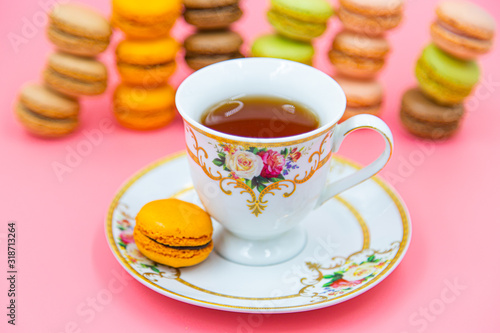 Cup of tea with Tasty Macaroon cookies on pink background. closeup Assortment Almond Dessert macaroni.