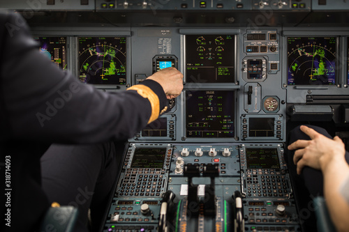 Pilot's hand dialing in flight values in a commercial airliner airplane flight cockpit during takeoff
