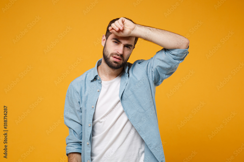 Tired exhausted young bearded man in casual blue shirt posing isolated on yellow orange wall background, studio portrait. People emotions lifestyle concept. Mock up copy space. Putting hand on head. Tired exhausted young bearded man in casual blue shirt posing isolated on yellow orange wall background, studio portrait. People emotions lifestyle concept. Mock up copy space. Putting hand on head.