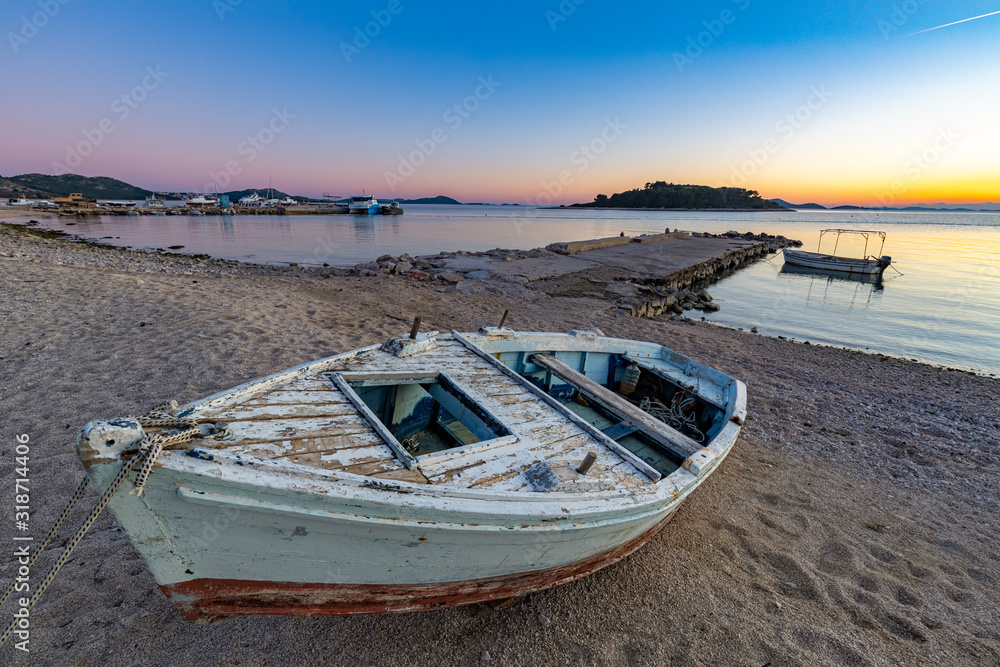 The beach at the Pakoštane with the old boat and Kornati islands in the background after the sunset, Croatia