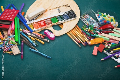 Different colored school supplies on blackboard
