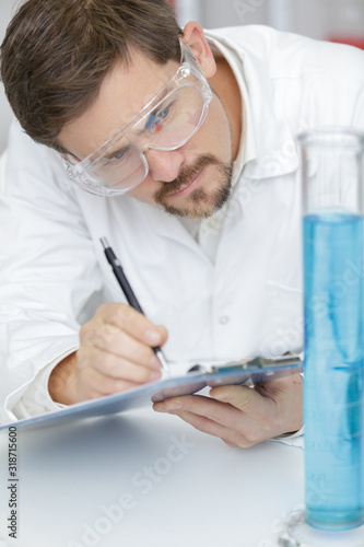 concentrated man scientist taking notes in lab