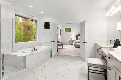 Master bathroom interior in new luxury home with marble floors and wall accents. Shows view of master bedroom photo
