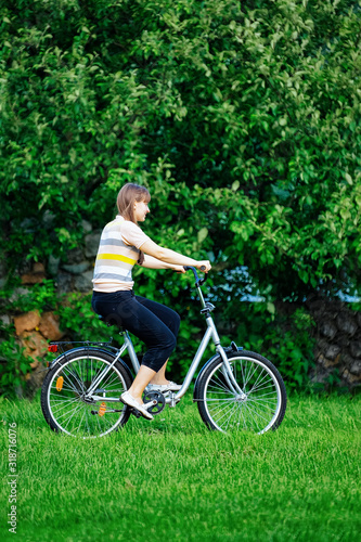 Young lady riding a bicycle at the park at Voronovo, Russia.