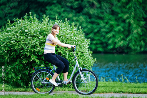 Fototapeta Naklejka Na Ścianę i Meble -  Young lady riding a bicycle at the park in Voronovo, Russia.
