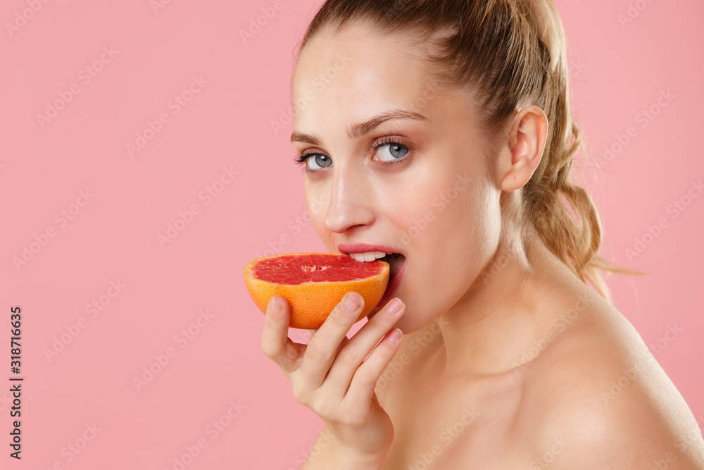 Close up blonde half naked woman 20s perfect skin nude make up blue eyes hold in hand grapefruit isolated on pastel pink background studio portrait. Skin care healthcare cosmetic procedures concept. Close up blonde half naked woman 20s perfect skin nude make up blue eyes hold in hand grapefruit isolated on pastel pink background studio portrait. Skin care healthcare cosmetic procedures concept.