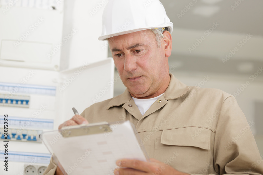portrait of electrician standing next to fuseboard portrait of electrician standing next to fuseboard