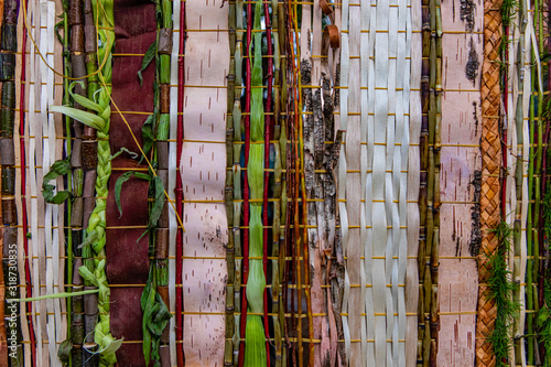 Closeup full frame shot of wooden bamboos and strips decoration with braided leaves representing abstract wampum in event outdoor photo