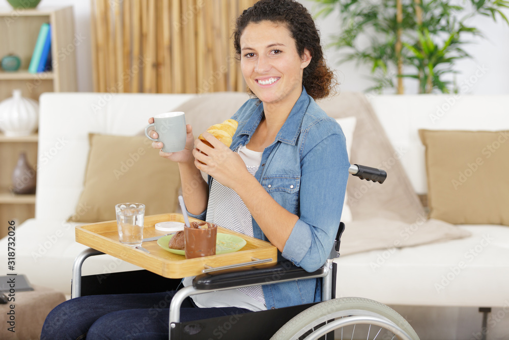 smiling pretty woman in wheelchair having breakfast in a kitchen smiling pretty woman in wheelchair having breakfast in a kitchen
