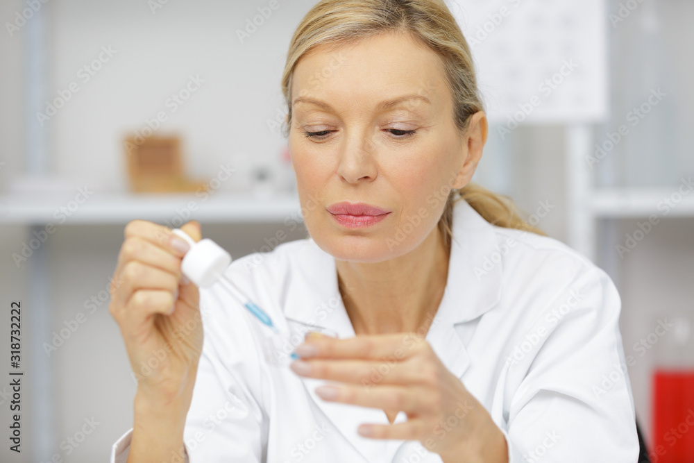 senior woman scientist adding liquid to test tube with pipette senior woman scientist adding liquid to test tube with pipette