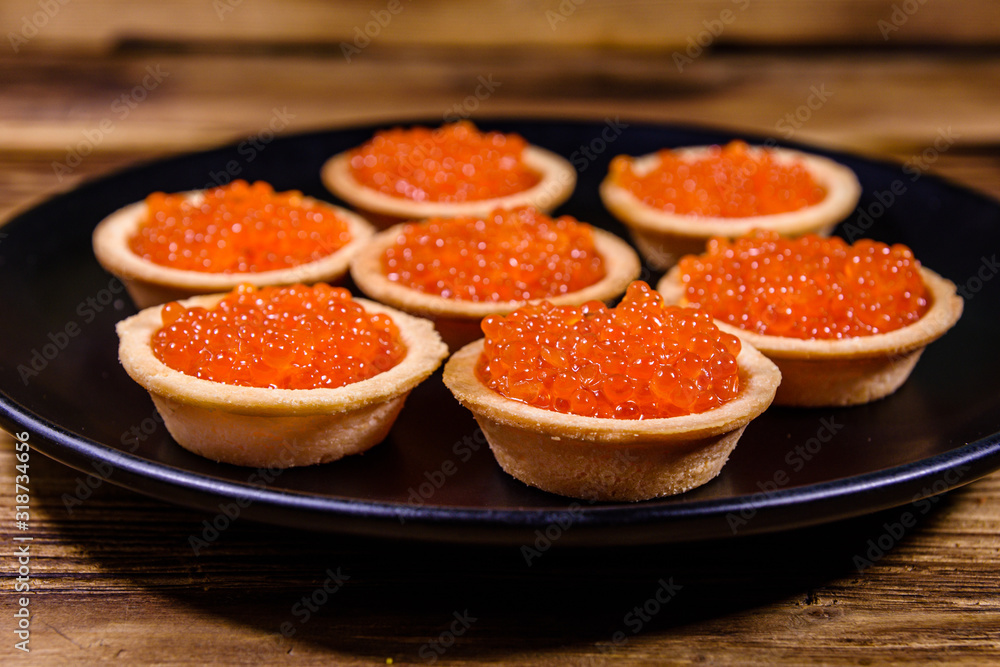 Tartlets with red caviar on a black plate. Festive food Tartlets with red caviar on a black plate. Festive food
