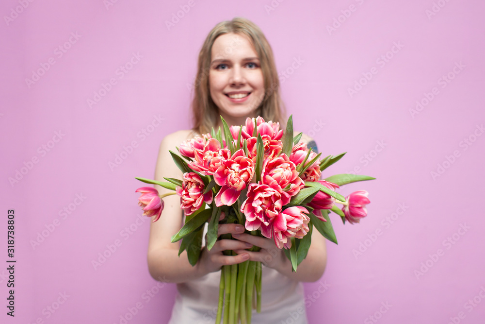 young beautiful girl holds a bouquet of flowers on a pink background, close-up of a bouquet of tulips young beautiful girl holds a bouquet of flowers on a pink background, close-up of a bouquet of tulips