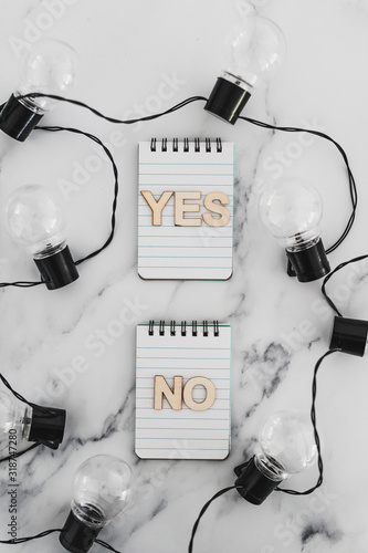 decision making process, group of notepads with yes and no options and string of light bulbs photo