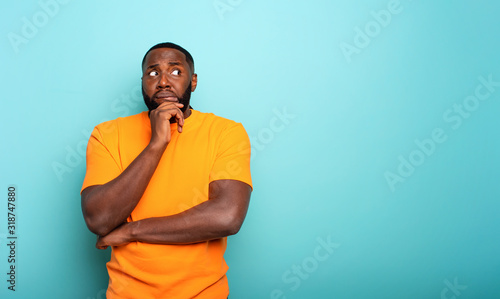 Confuse and pensive expression of a boy . cyan colored background photo
