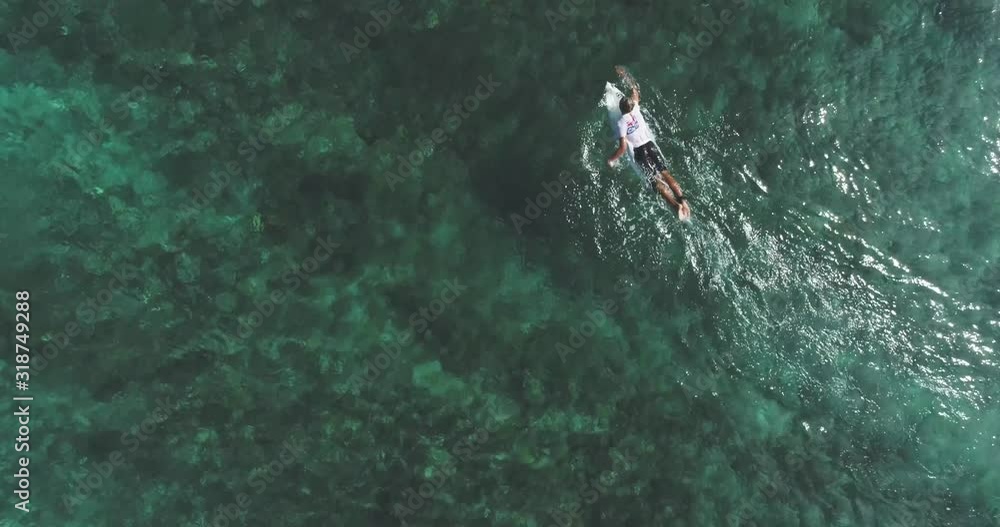Top down aerial shot on surfers catching waves at the ocean. Bird eye view high on seawater with surfing board at the pacific Top down aerial shot on surfers catching waves at the ocean. Bird eye view high on seawater with surfing board at the pacific