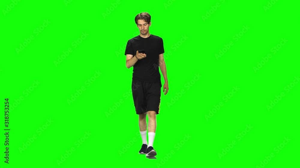 Brunette man goes and texting with smartphone on green screen at studio. Brunette man goes and texting with smartphone on green screen at studio.