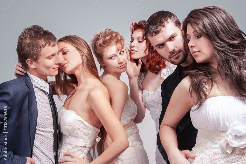 Obraz premium Closeup of Group of Five Loving Caucasian People Standing in Pairs of Two in Wedding Clothing. Against Gray Background.