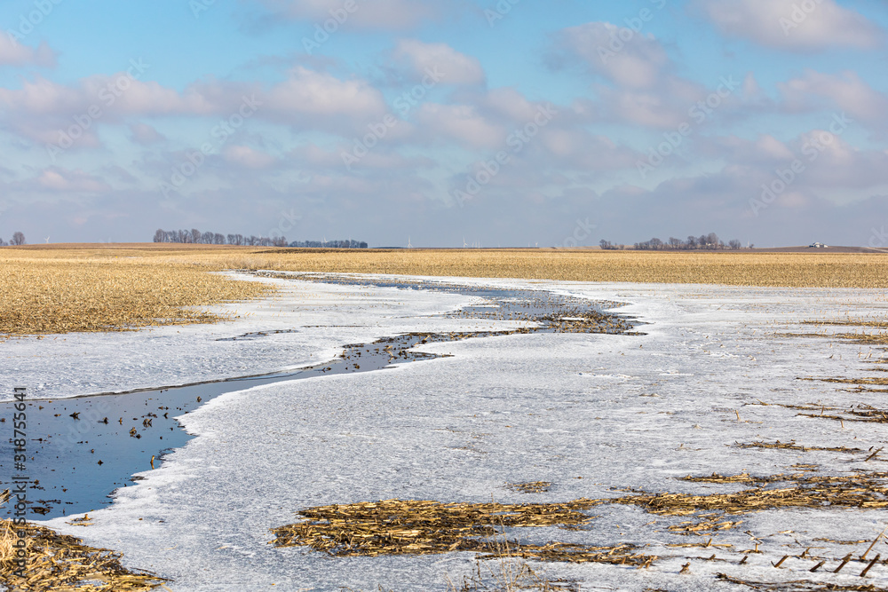 Flooded farm field after winter rain storms with water turning to ice as temperature dropped below freezing