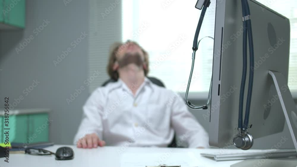 Doctor sit at a table and sleep on the background of stethoscope Doctor sit at a table and sleep on the background of stethoscope