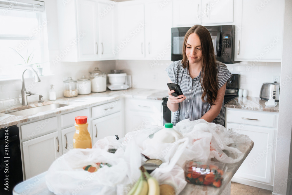 Lifestyle of women unloading her groceries at home in a white kitchen Lifestyle of women unloading her groceries at home in a white kitchen