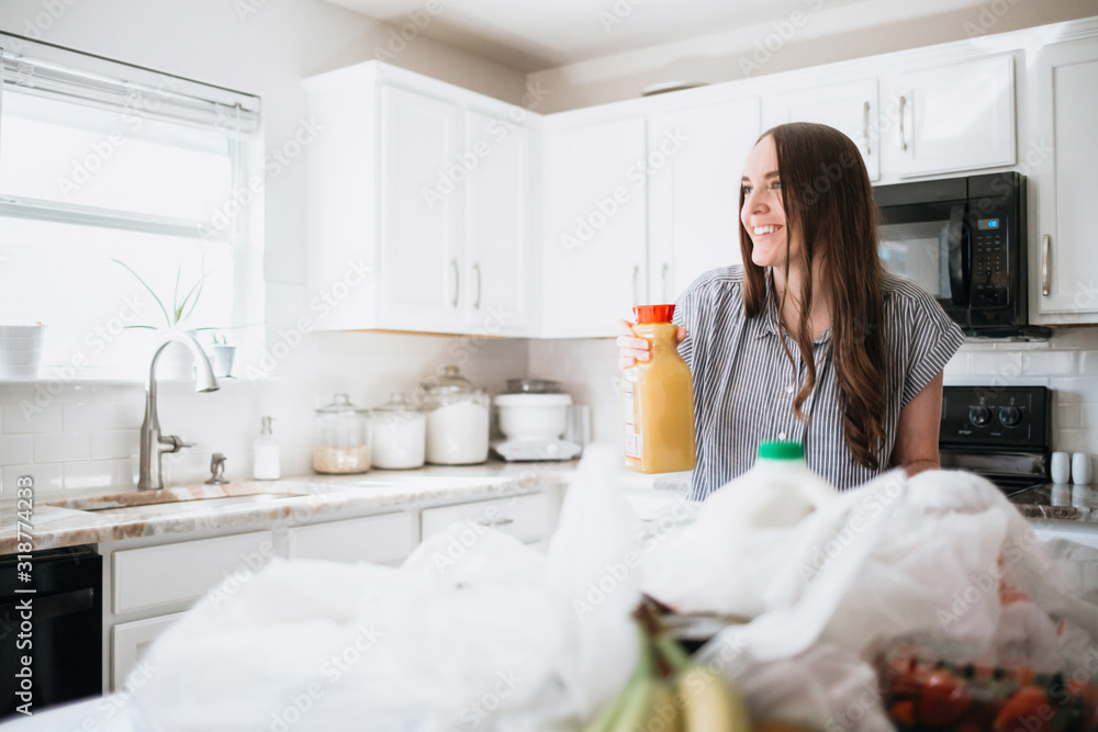 Lifestyle of women unloading her groceries at home in a white kitchen Lifestyle of women unloading her groceries at home in a white kitchen