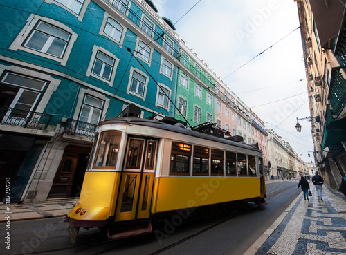 Yellow electric tram on old streets and colorful buildings of Lisbon, Portugal, popular tourist attraction commercial square