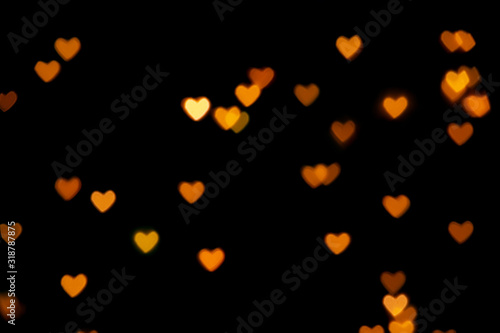 Black background with bright warm heart shaped bokeh lights. Holiday, Valentines Day background. Ideal to layer with any design. Horizontal
