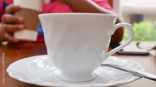 White cup and spoon on wood table.