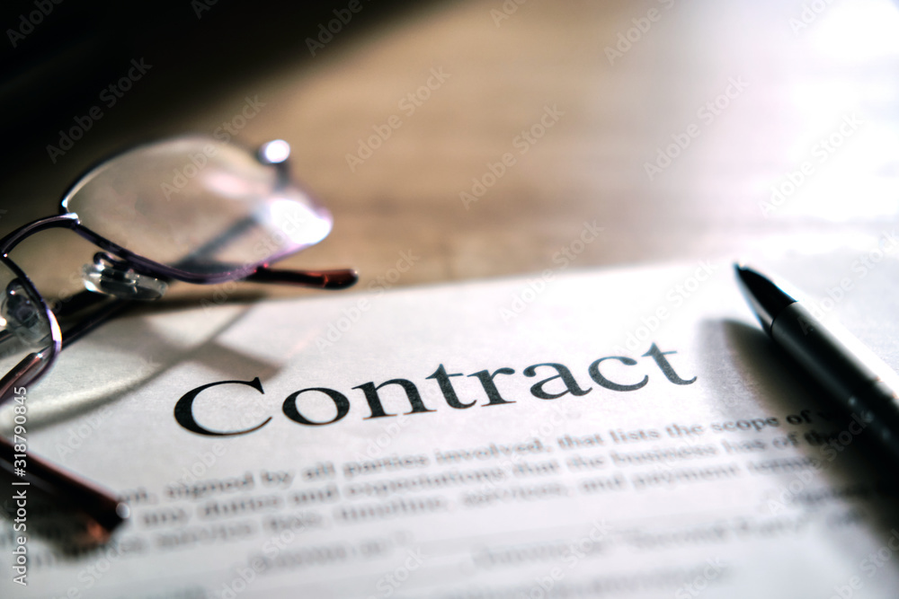 Contract sheet with glasses and a pen on a wooden background Contract sheet with glasses and a pen on a wooden background