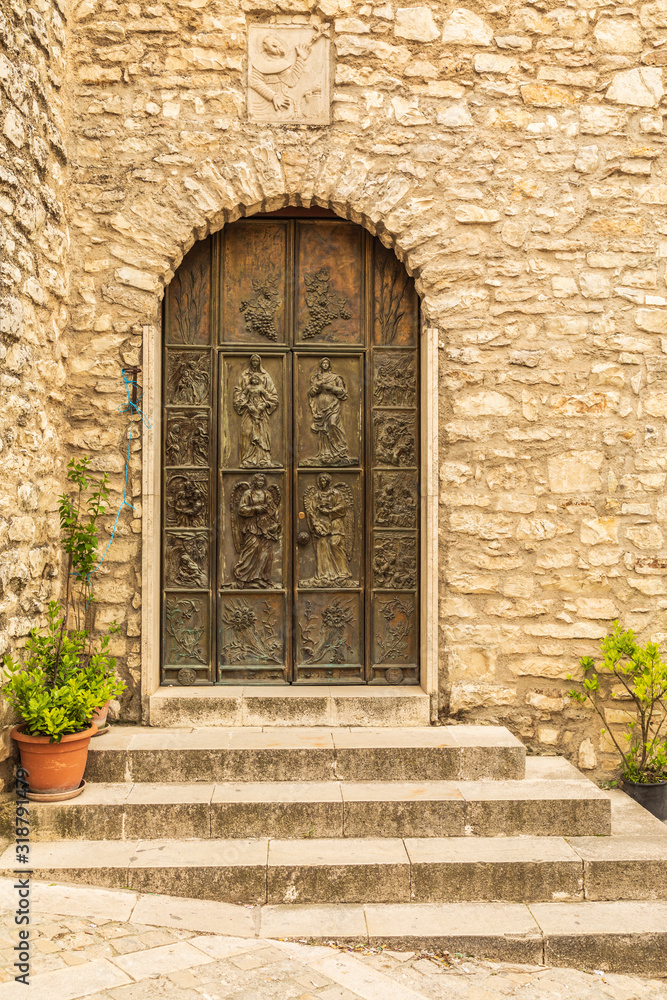 Italy, Sicily, Province of Palermo, Prizzi. Carved wooden door and a stone wall in Prizzi.