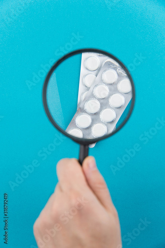 Pharmaceutical research and clinical trials concept. New medical drug in pills under magnifying glass.