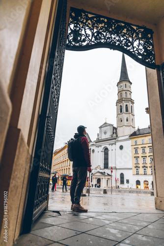 man tourist in raincoat with backpack looking at saint michaels church photo