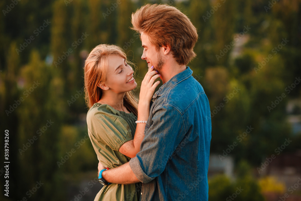 A young couple cuddles in the sunset rays of the summer sun. Real emotions and romance. A young couple cuddles in the sunset rays of the summer sun. Real emotions and romance.