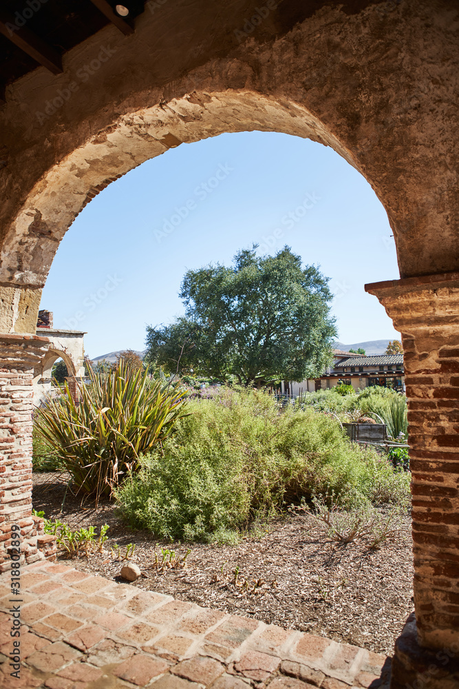 Court Yard in a Historic Spanish Mission Church in California During the Day Framed Through an Arch and Pillars