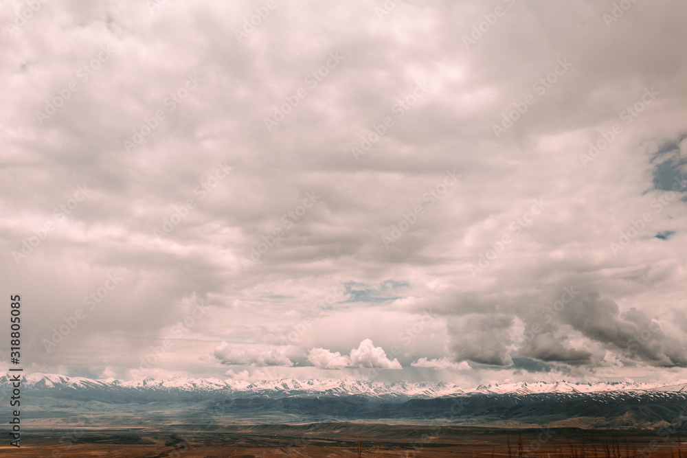 Landscape with mountains, clouds, water, and roads in a Central Asian country