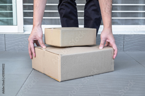 Man's hand holding boxes at the front door to receive package, shipping delivery concept © Thitiphat