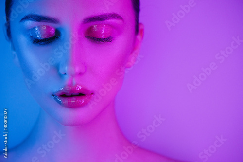 High Fashion woman in colorful bright neon uv blue and purple lights, posing in studio, beautiful girl, glowing make-up, colorful make up.